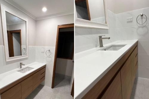 a white bathroom with two sinks and a mirror at Haven On Jones in Mollymook