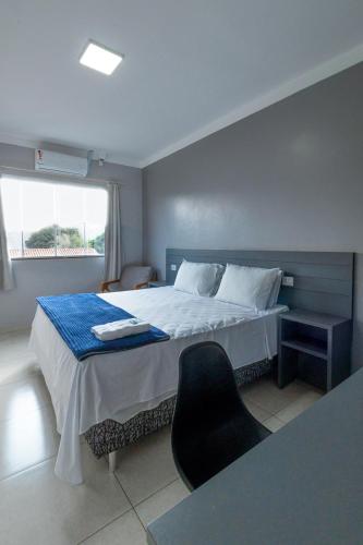 UbiratãにあるEuro Hotelのベッドと椅子と窓のある寝室