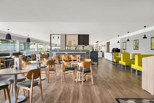 a restaurant with tables and chairs in a cafeteria at Holiday Inn Norwich, Ipswich Road by IHG in Norwich