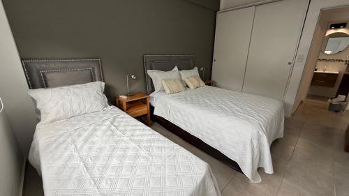 - 2 lits dans une petite chambre avec jupes dans l'établissement Departamento Ama con estacionamiento para vehículos chicos, à Villa Dolores