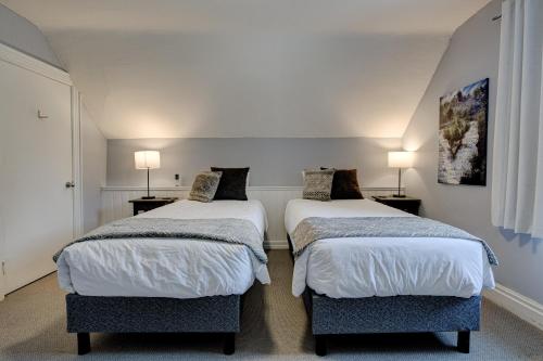 two beds in a small room with two lamps at Historic Home in the Heart of Elora in Elora