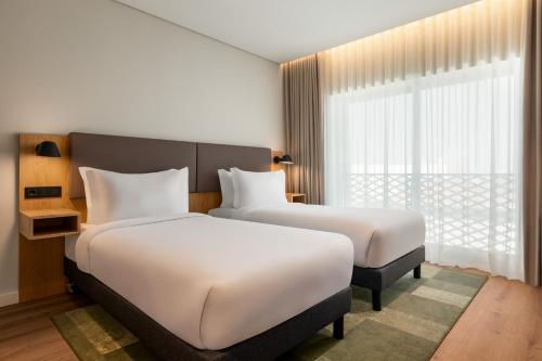 two beds in a hotel room with a window at Holiday Inn Beja by IHG in Beja
