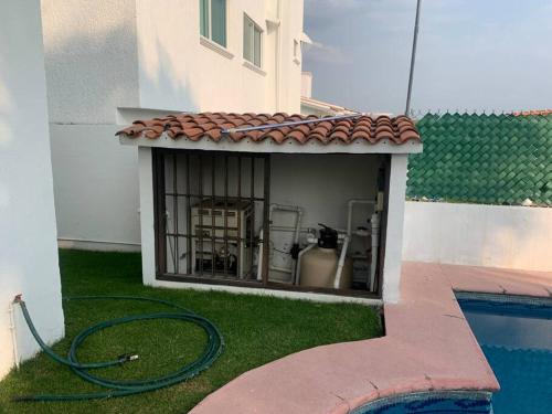 a swimming pool with a hose next to a building at Residencia con alberca privada y jacuzzi en Lomas de Cocoyoc in Oaxtepec