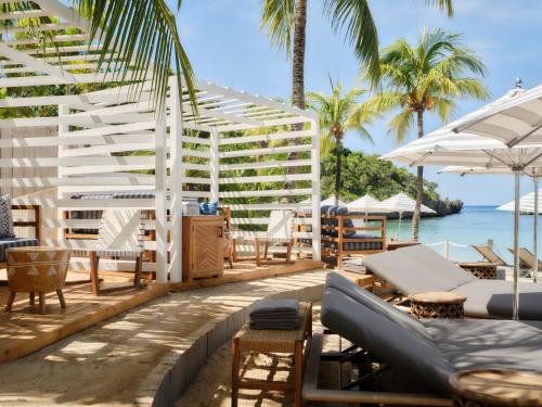 a patio with chairs and umbrellas and the ocean at Kimpton - Grand Roatan Resort and Spa in West Bay