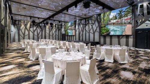 a room with white tables and chairs and a screen at Crowne Plaza Changi Airport by IHG in Singapore
