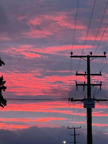 a sunset over the water with two electricity poles at Sunset Motel in Fox Glacier