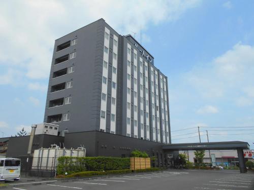 a tall gray building with a parking lot at Hotel Route-Inn Kikugawa Inter in Kikugawa