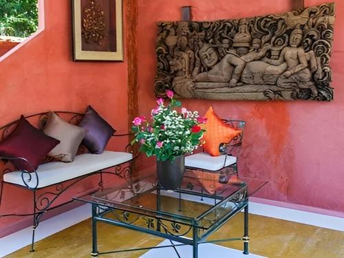 a room with a bench and a vase with flowers on a table at Insda Wellness Resort in Chiang Mai
