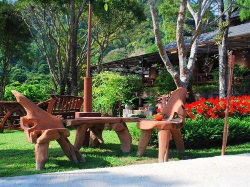a picnic table and benches in a park with flowers at Insda Wellness Resort in Chiang Mai