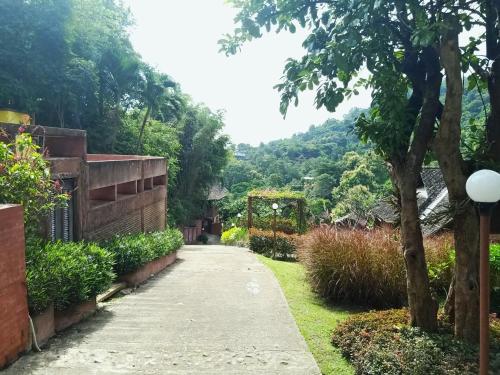 a walkway leading to a garden with trees and bushes at Insda Wellness Resort in Chiang Mai