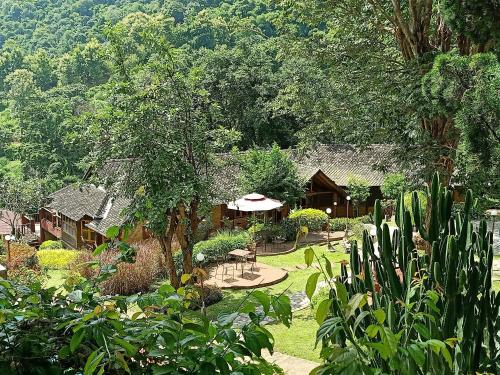 a garden with a house in the background with trees at Insda Wellness Resort in Chiang Mai