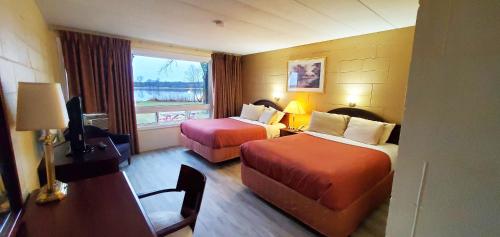 a hotel room with two beds and a desk at Riverview Motel in Dunnville