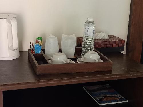 a tray with tea cups and a bottle of water on a table at Insda Wellness Resort in Chiang Mai