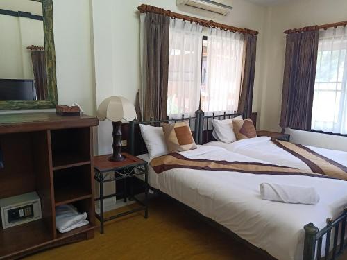 a bedroom with a large bed and a mirror at Insda Wellness Resort in Chiang Mai