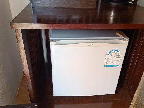 a small white refrigerator under a wooden table at Insda Wellness Resort in Chiang Mai