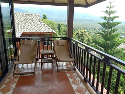 a balcony with two chairs and a view of the mountains at Insda Wellness Resort in Chiang Mai
