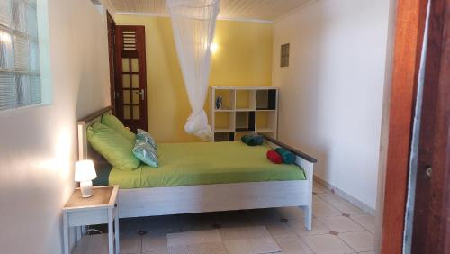 une petite chambre avec un lit vert dans une pièce dans l'établissement Entre mer et montagne, à Saint-Claude