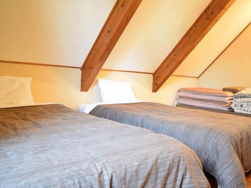 two beds in a room with wooden ceilings at PICA Yamanakako Village in Yamanakako
