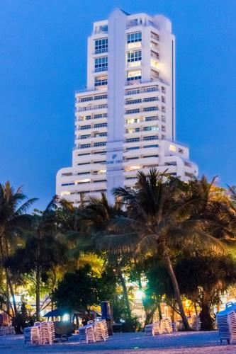 a tall white building with palm trees and chairs at Patong Tower Holiday Rentals in Patong Beach
