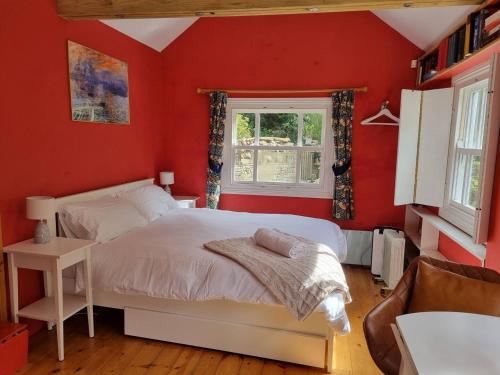 a red bedroom with a bed and a window at Roses Cottage and Studio in Bideford
