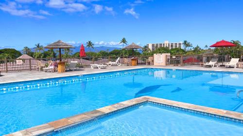 a large blue swimming pool with chairs and umbrellas at Maui Eldorado D200 - 2 Bedroom in Lahaina