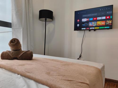 a teddy bear sitting on a bed with a tv on the wall at K Avenue Modern Style Studio (5 Mins to Airport) in Kota Kinabalu