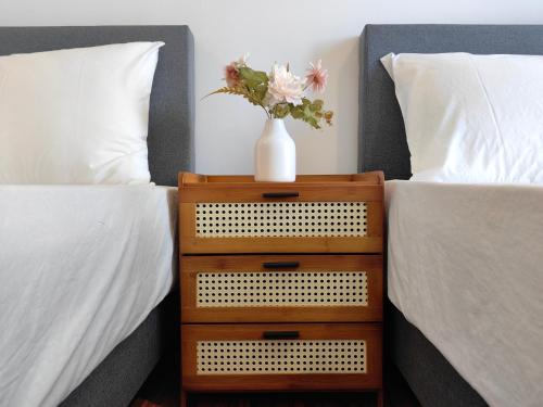 a vase of flowers on a nightstand between two beds at K Avenue Modern Style Studio (5 Mins to Airport) in Kota Kinabalu