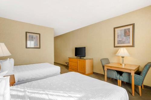 a hotel room with two beds and a desk and a tv at Best Western PLUS Revere Inn & Suites in Paradise
