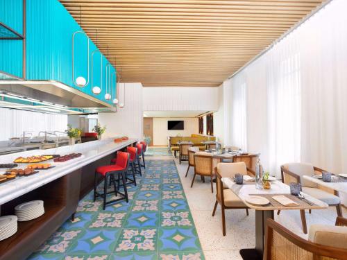 a restaurant with tables and chairs and a cafeteria at Novotel Goa Panjim in Panaji