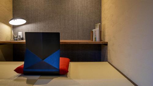 a room with a chair and a shelf with books at Hanare no yado Kamigakure in Takachiho