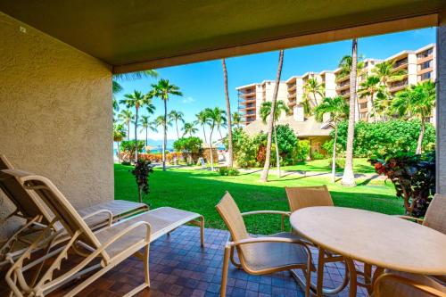 a patio with a table and chairs and a view of a yard at Napili Point by KBM Resorts in Kaanapali