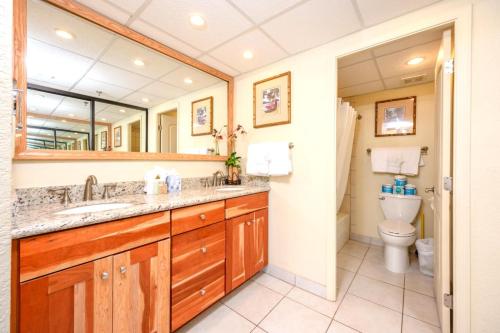 a bathroom with a sink and a toilet and a mirror at Napili Point by KBM Resorts in Kaanapali