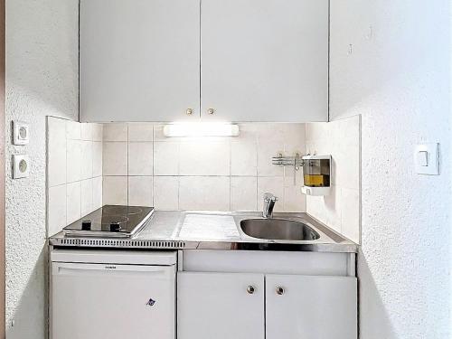 Elle comprend une petite cuisine avec un évier et des placards blancs. dans l'établissement Studio confort au Corbier - Skis aux pieds & Balcon - FR-1-267-298, à Villarembert