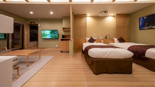 a hotel room with two beds and a flat screen tv at Hanare no yado Kamigakure in Takachiho