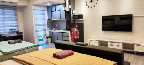 a room with a bed and a kitchen with a tv at Spacious 2 King Bed Family Room 56 Sqm PODOMORO APARTMENT Tower Liberty 21st Floor with Mall Direct Access in Medan