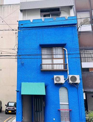 a blue building with a window and a balcony at ゲストハウスROOASiS常磐町501 in Takamatsu