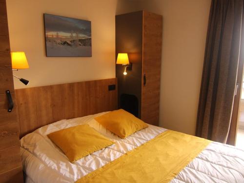 - une chambre avec un lit et 2 oreillers jaunes dans l'établissement Appartement 3 pièces avec parking couvert, proche commodités - FR-1-594-331, à Hauteluce