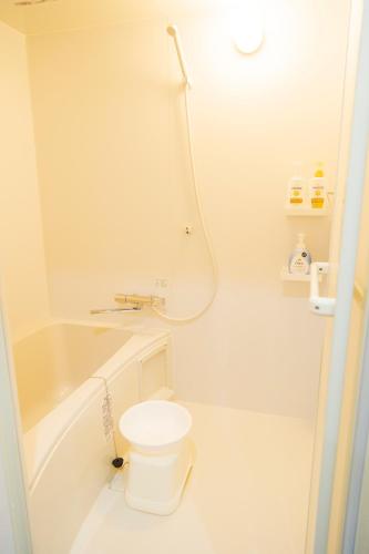 a white bathroom with a toilet and a bath tub at 貸切戸建て Private House Sleep Man in Kagoshima