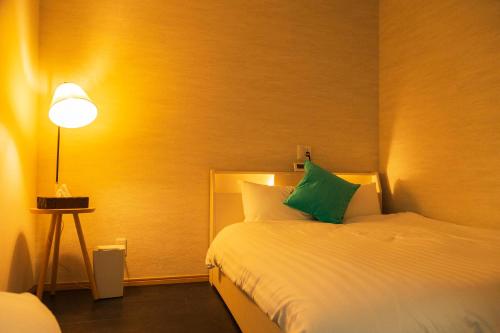 a hotel room with a bed with a green pillow at 貸切戸建て Private House Sleep Man in Kagoshima