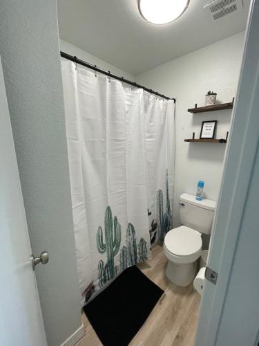 a bathroom with a toilet with a cactus shower curtain at Rustic Farmhouse Old Town Condo W Patio & Pool in Scottsdale
