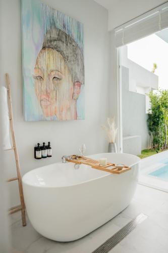 a white bath tub in a bathroom with a painting at Beachfront Secret Tides Villa Mar in Bangrak Beach