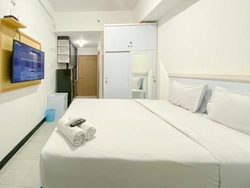 a bedroom with a large white bed with towels on it at Comfy and Modern Studio at Cordova Edupartment Semarang Apartment By Travelio in Semarang