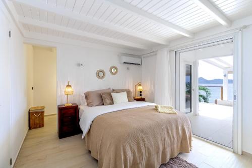 a white bedroom with a bed and a balcony at Casa dulce - Camaruche in Saint Barthelemy