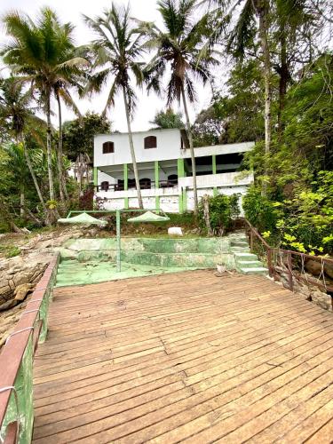 a wooden boardwalk leading to a building with palm trees at Pousada Ponta da Ilha, Ilha Grande, Angra dos Reis in Angra dos Reis