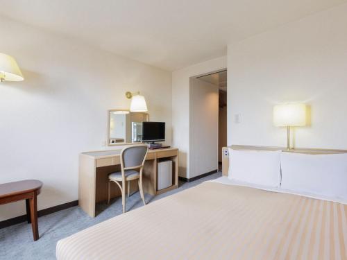 a hotel room with a desk with a computer and a bed at FLEXSTAY INN Kashima Central in Kamisu