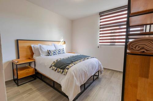 a bedroom with a bed with a night stand and a window at Lofts By Verticca in Santa Cruz Tecamac