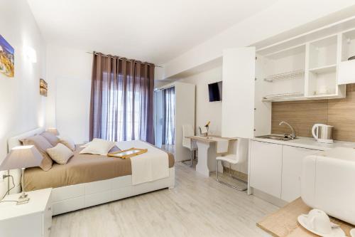 a bedroom with a bed and a desk and a kitchen at Sette Colli Guesthouse in Cagliari
