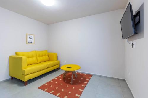 a living room with a yellow couch and a table at Lofts By Verticca in Santa Cruz Tecamac