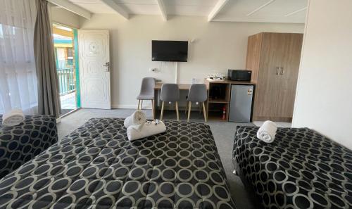a bedroom with two beds and a kitchen with a table at Fig Tree Motel in Narrandera