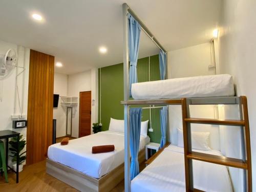 a bedroom with two bunk beds and a desk at Sleepy Station Hostel in Kata Beach